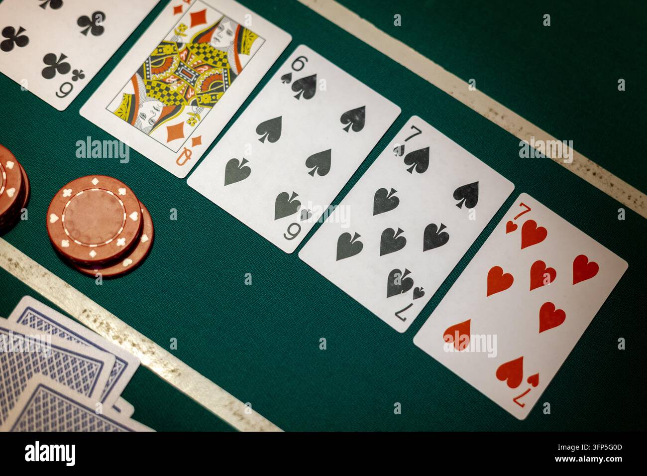 Grünes Pokerspiel-Brett zeigt fünf offene Spielkarten in einer Reihe neben runden roten Spielchips. Brett zeigt Herzbube sechs, Karo-Dame, Pik sechs. Stockfoto
