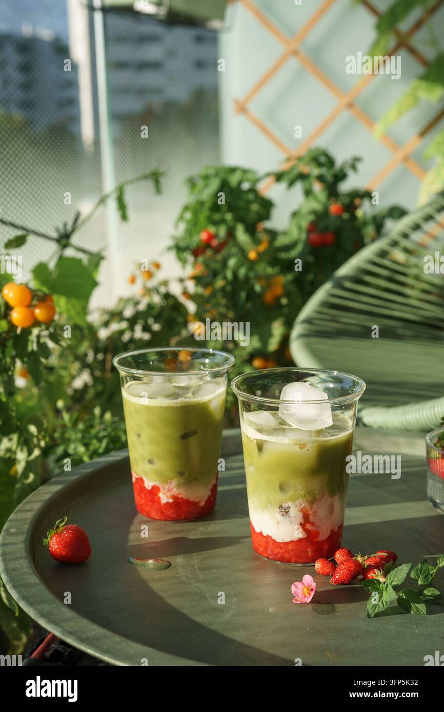 Erdbeer-Matcha-Lattes auf einem sonnigen Gartentisch Stockfoto