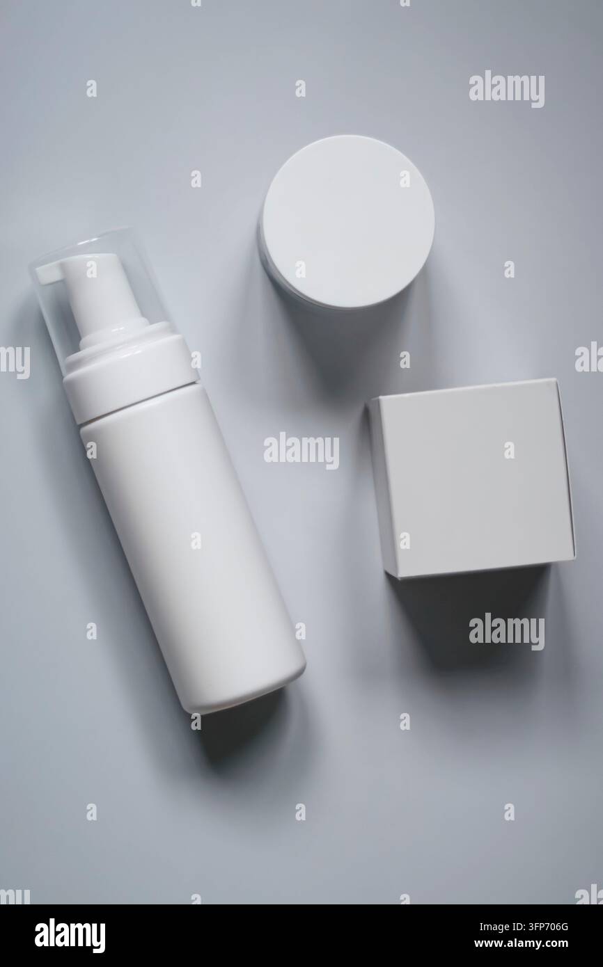 Weiße Kosmetik-Pumpflasche, Schraubdeckel-Glas und Kartonschachtel-Modell, die auf einem hellgrauen Hintergrund für Produktbranding liegen Stockfoto