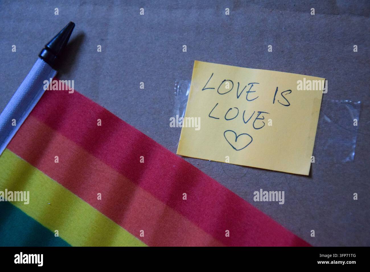 Love Is Love Botschaft mit Regenbogen-Pride-Flagge auf Karton Stockfoto