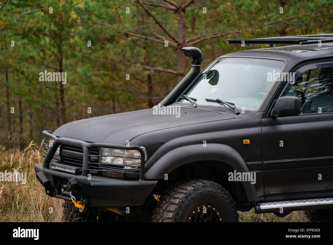 Modifiziertes Geländewagen-SUV mit Schnorchel, Bullenbar, Seilwinde und robusten Reifen, geparkt in einem Waldgebiet, ausgestattet für Freizeit-Fahrten und Fahrzeugbergung Stockfoto