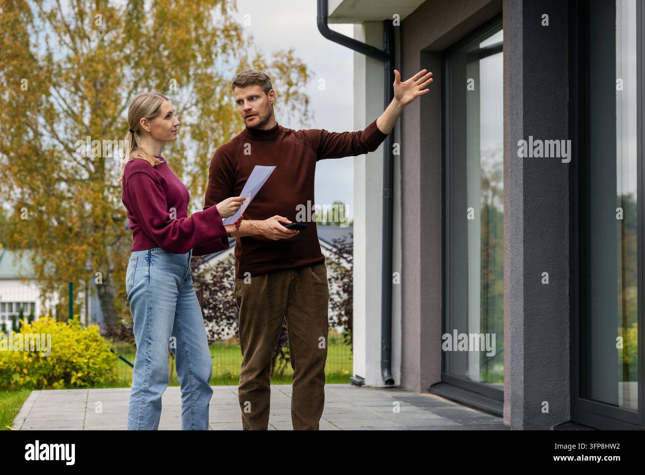 Immobilienmakler zeigt einem Kunden ein modernes Haus. Makler und Kunde inspizieren die Immobilie vor dem Kauf Stockfoto