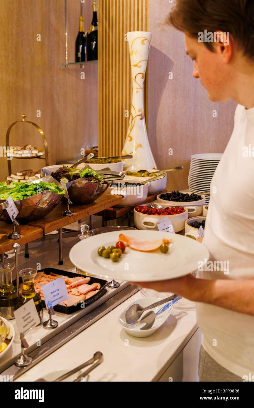 • Nahaufnahme von köstlichen Salatschüsseln und Catering-Gerichten auf einem Premium-Resort-Restaurant-Frühstücksbuffet mit einem nicht erkennbaren Mann. Stockfoto