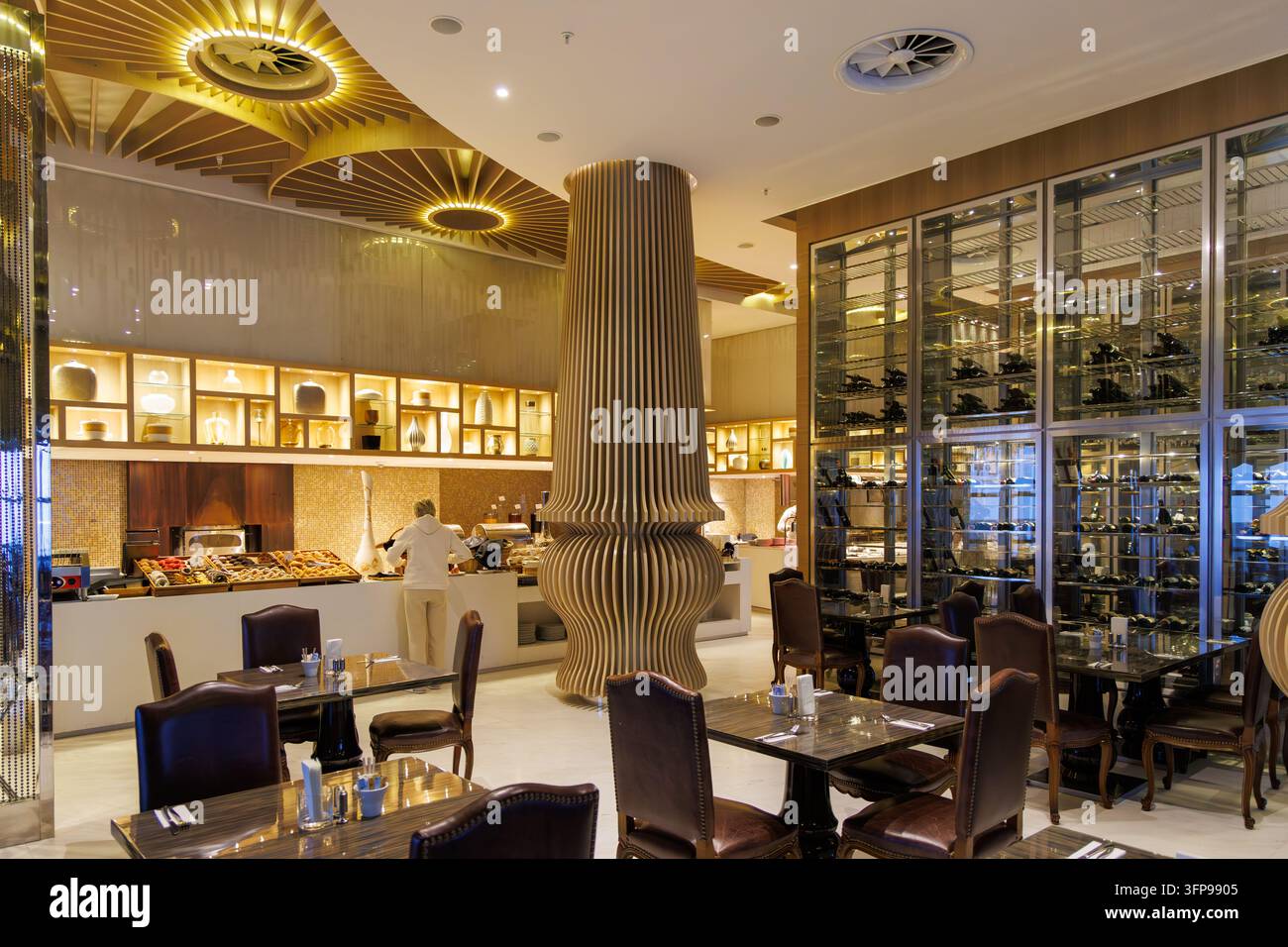 Breite horizontale Perspektive eines Premium-Resort-Restaurants mit einer futuristischen Holzsäule, Buffetbereich und eleganten Glas-Weinregalen. Stockfoto