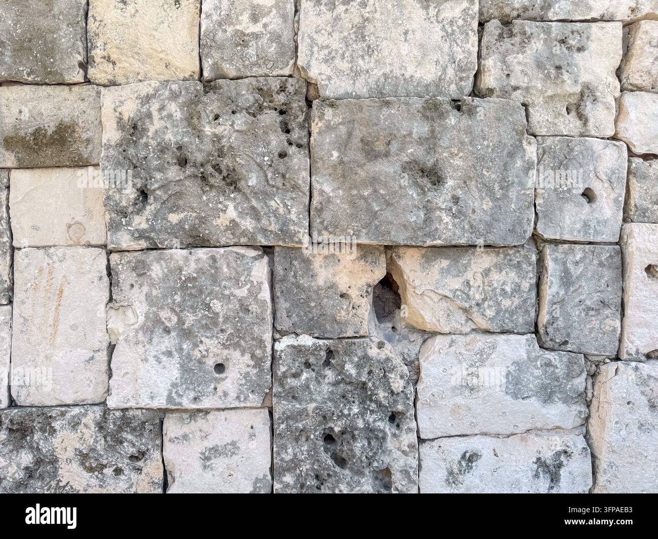 Alte Maya-Kalksteinmauer mit porösem Korallenstein – Historischer archäologischer Texturrückgrund Stockfoto