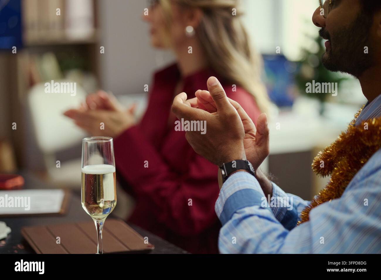 Indischer Mann klatscht in die Hände bei einer Firmenfeier zu Weihnachten Stockfoto