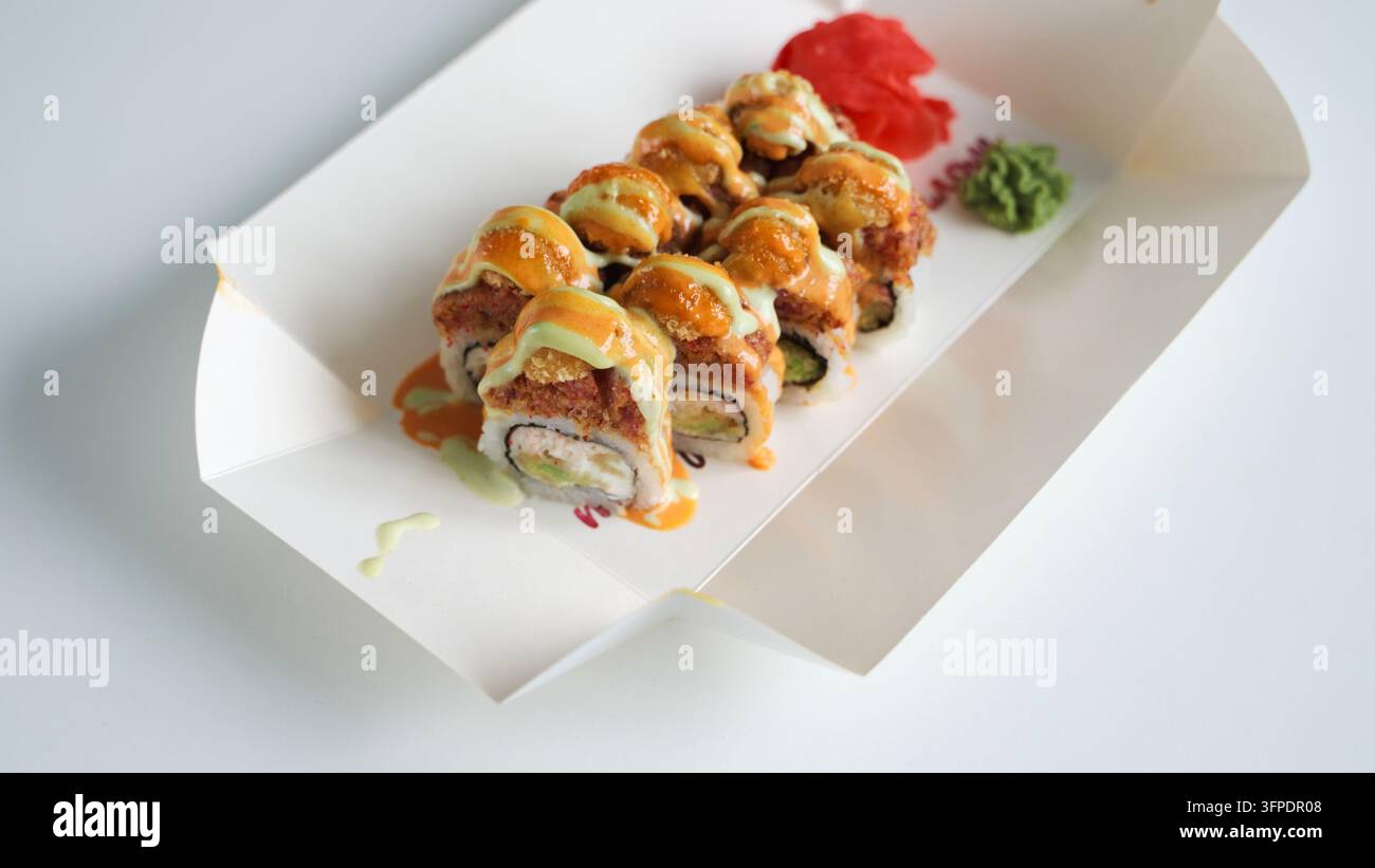 Sushi-Rollen mit Saucen und Belägen in einer Lieferbox, Genießen einer japanischen Take-away-Mahlzeit zu Hause Stockfoto