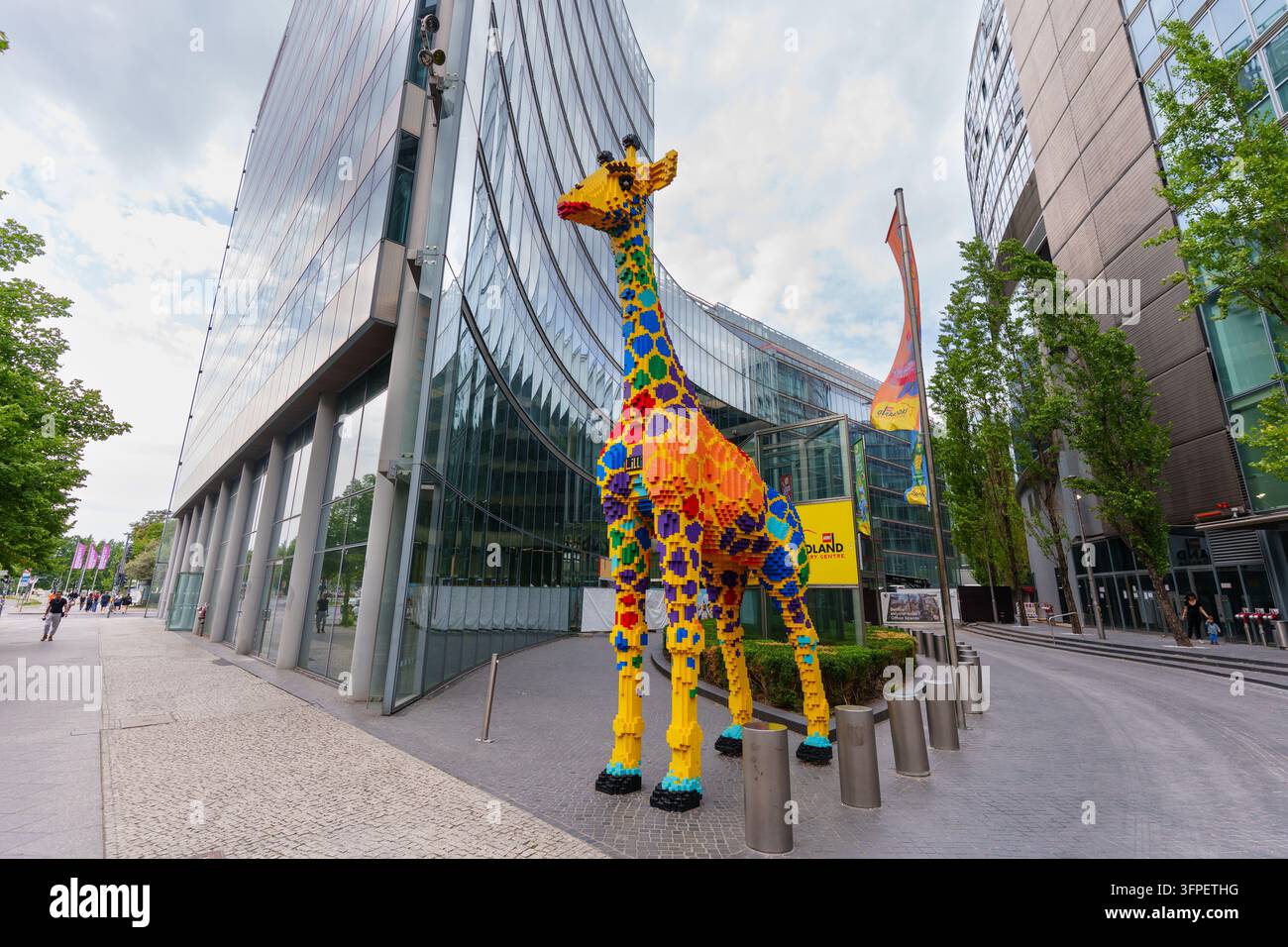 Berlin, Deutschland – 28. August 2026: Vollständige Ansicht einer massiven Giraffenstatue aus Spielzeugbausteinen, die auf dem Gehweg vor zeitgenössischen Glasgebäuden am Pots steht Stockfoto