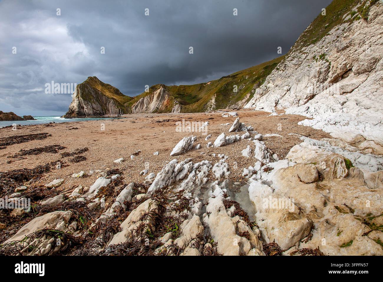 Man O'War Cove und Strand an der britischen Dorset Jurassic Coast mit dramatischen Sturmwolken, die sich über den schroffen Kalksteinklippen sammeln Stockfoto