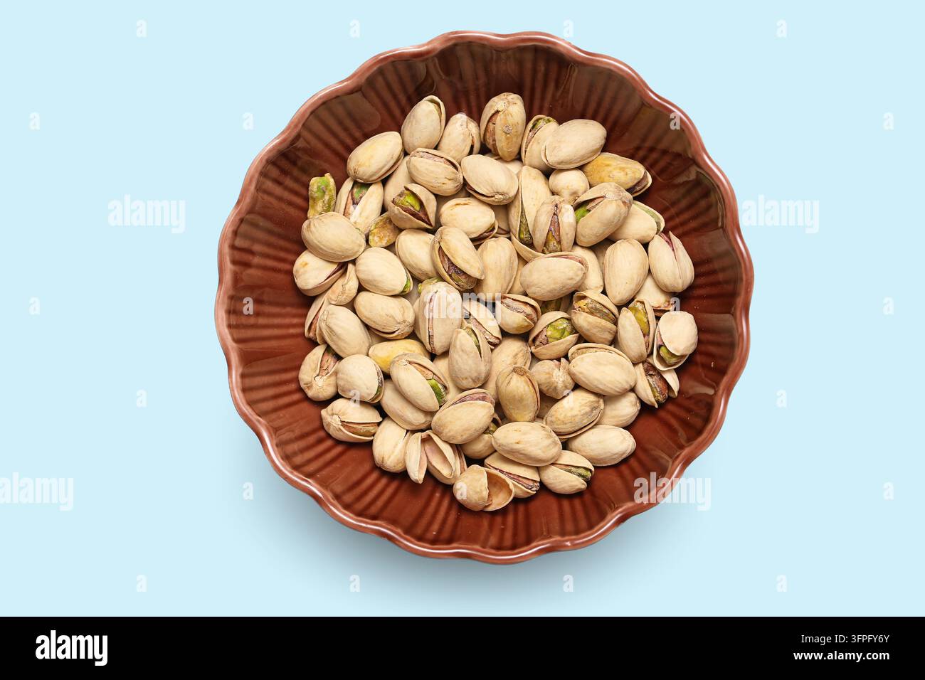 Pistaziuschalen in brauner Schale auf blauem Hintergrund. Gesunde Snack-Komposition für Protein, Ernährung und vegetarische Nahrung. Stockfoto