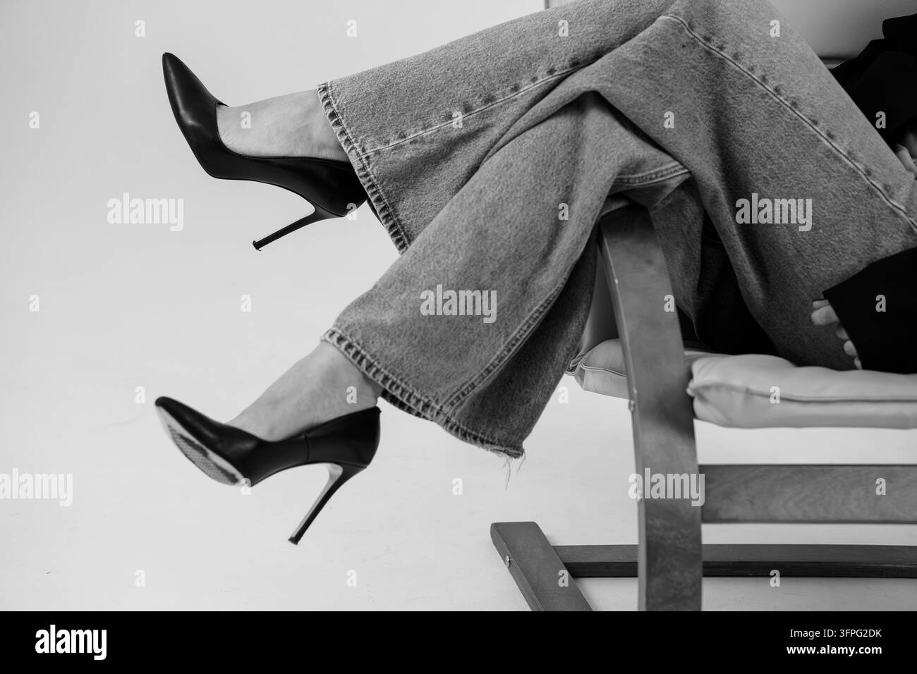 Redaktionelles Monochrom-Foto von stilvollen weiblichen Füßen in spitzen High-Heel-Schuhen, mitten in der Bewegung mit dramatischer Pose für Magazin oder Anzeige aufgenommen Stockfoto