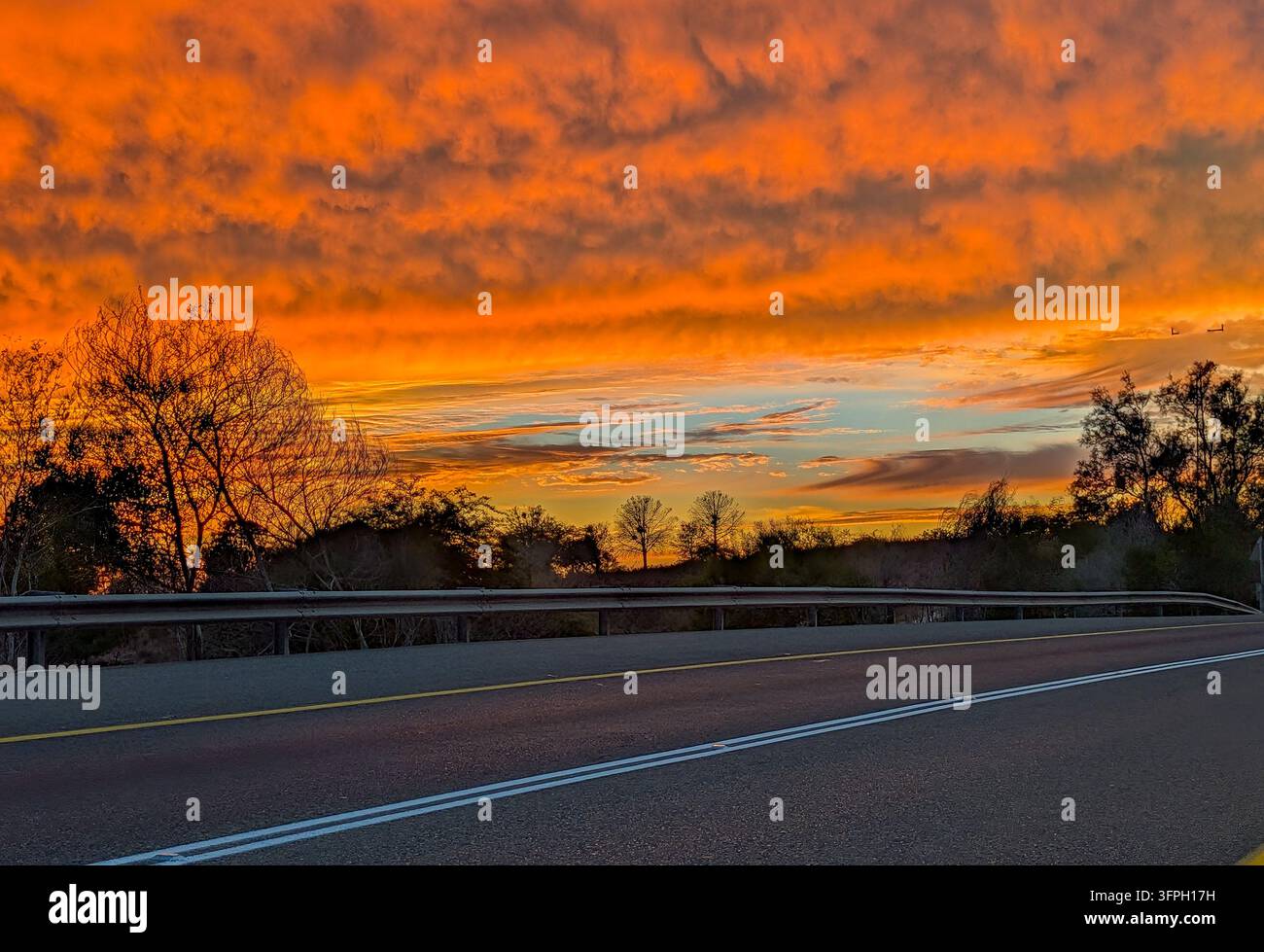 Dramatischer leuchtender Sonnenuntergang färbt die Wolken in einem Schattier von Orange, Rosa und Schwarz Stockfoto