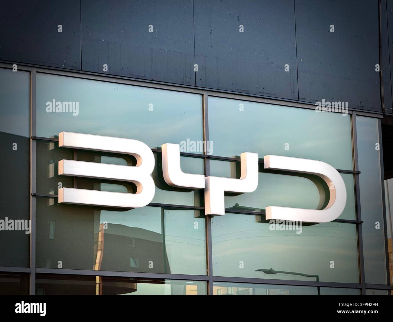 Ein modernes BYD-Autohandelsgeschäft mit weiß beleuchteter BYD-Logo-Schilderei - Smartphone-aufgenommenes Stockfoto