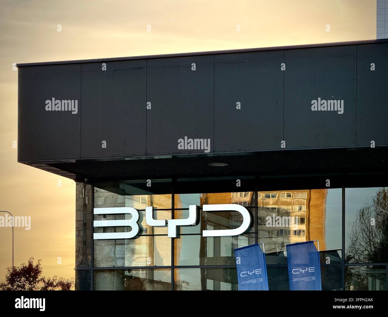 Ein modernes BYD-Autohandelsgeschäft mit weiß beleuchteter BYD-Logo-Schilderei - Smartphone-aufgenommenes Stockfoto