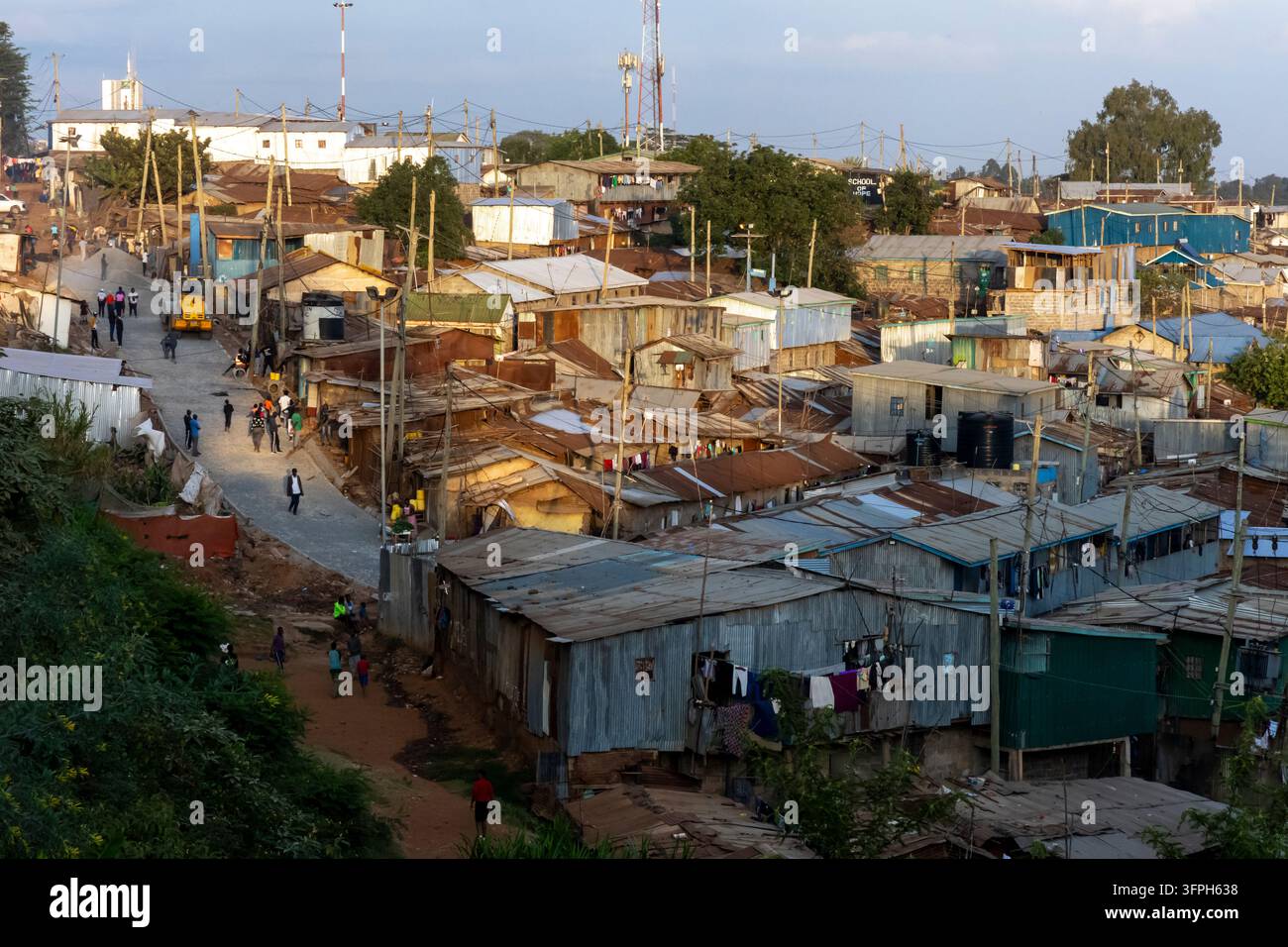 Erhöhte Ansicht von Wellblechdächern und einer neu gepflasterten Gasse mit Fußgängern im Kibera-Gebiet bei Sonnenuntergang, Nairobi County, Nairobi, Kenia Stockfoto