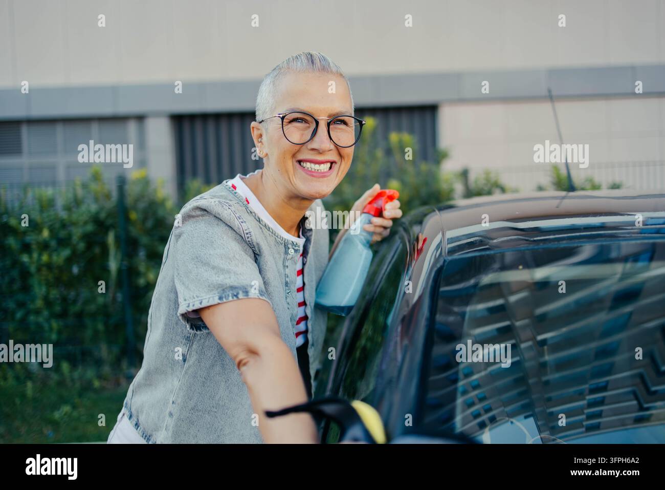 Eine Frau wischt ihr Auto mit einem Tuch ab. Hochwertiges Foto Stockfoto