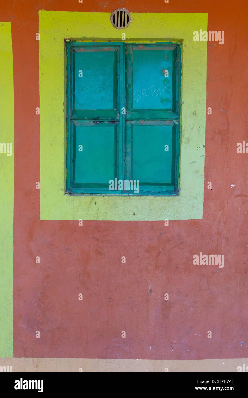 Grüne Metallfensterläden, die in Gelb auf einer orange gestrichenen Wand am Lake Turkana Cultural Festival, Marsabit County, Loiyangalani, Kenia eingerahmt sind Stockfoto