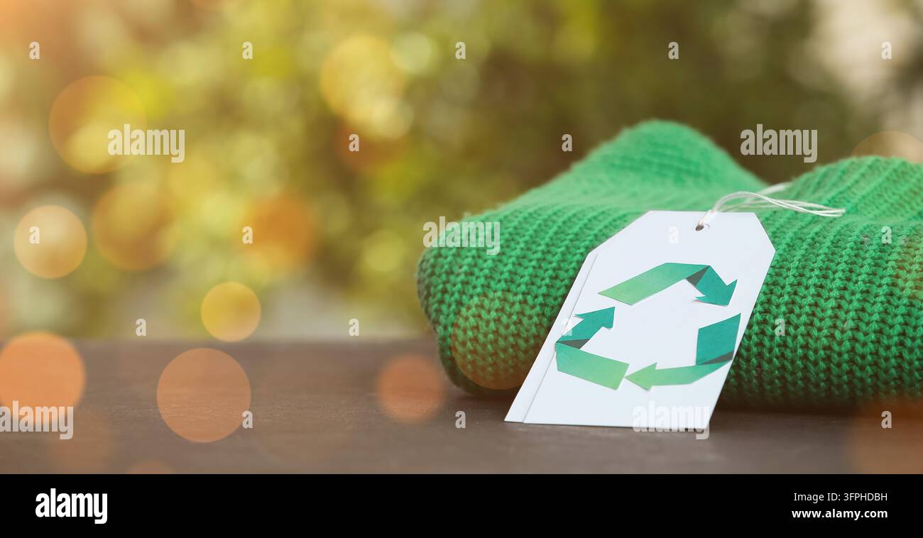 Nachhaltige Mode und Kreislaufwirtschaft, grüner gestrickter Pullover mit einem Recyclingsymbol-Tag für umweltfreundliche Kleidung und ethischen Konsum Stockfoto