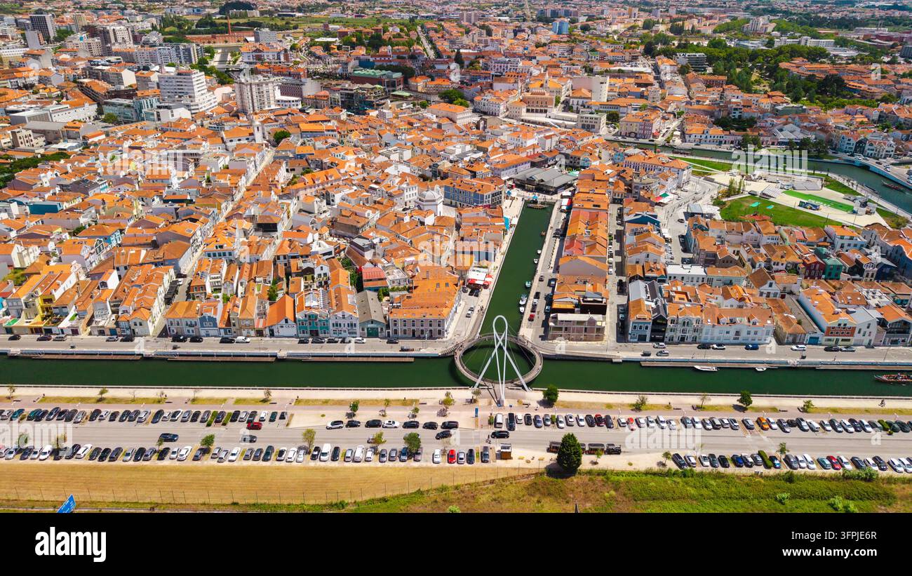 Luftbild von Aveiro, Portugal, das dichte historische Stadtblöcke, orangefarbene Dächer, einen Kanal, eine Brücke und einen Parkplatz am Wasser zeigt Stockfoto