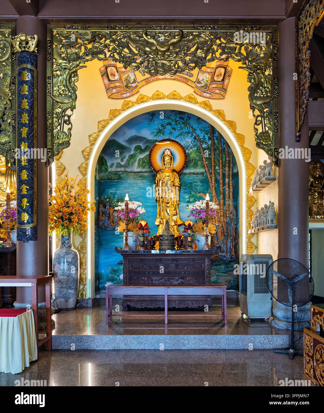Goldene Statue von Quan Am im prächtigen Altar der Linh Ung Pagode in Da Nang, Vietnam, mit traditionellen Dekorationen und Blumenarrangements Stockfoto