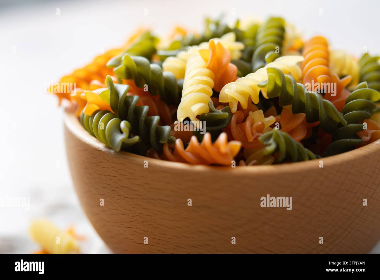 Trockenes tricolor Fusilli-Nudelgericht in einer Schüssel auf Holztablett Stockfoto