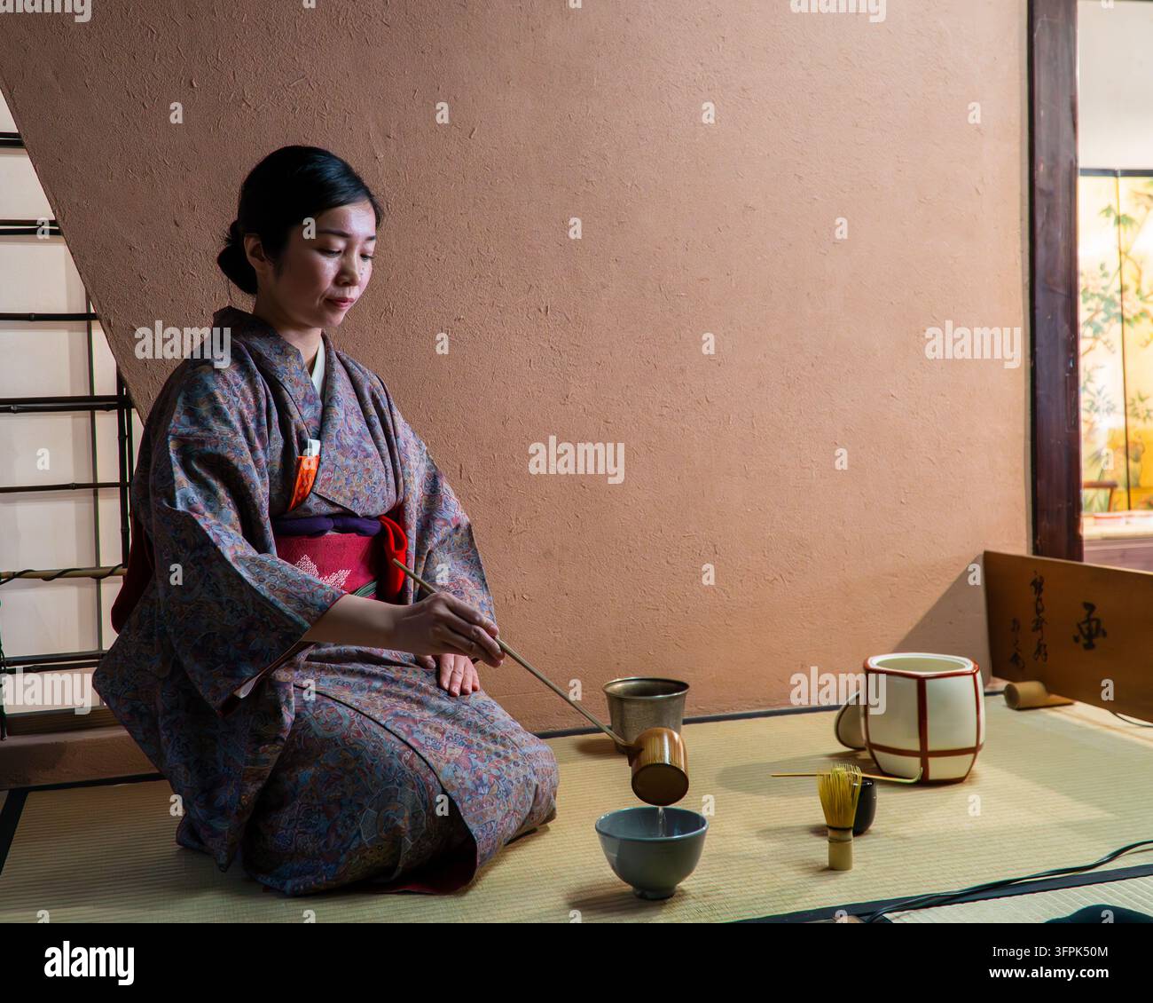 Japanische Teeceremonie mit einer Frau in einem traditionellen Kimono in einem Tatami-Raum in Kyoto, Japan. Stockfoto
