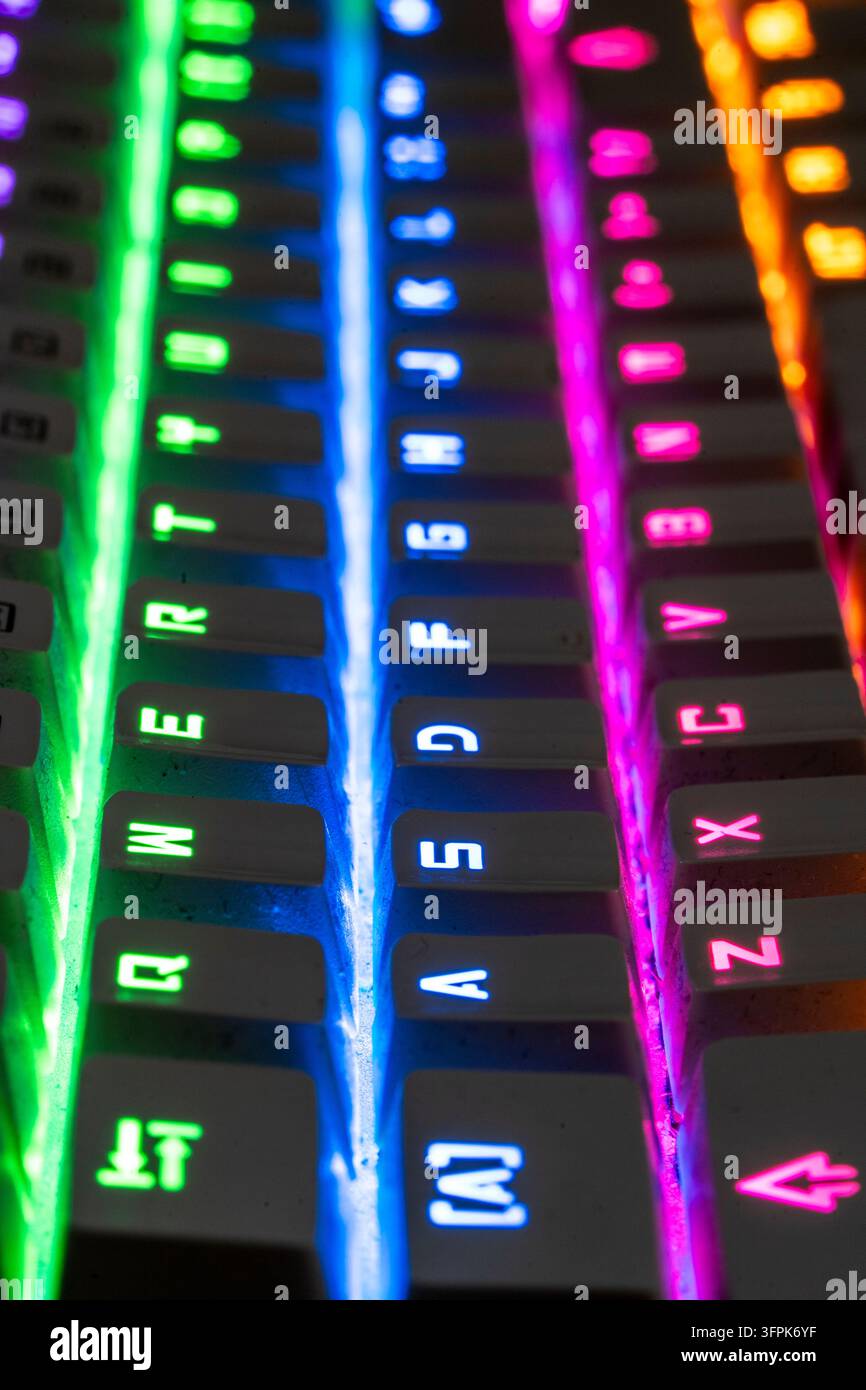 Ansicht einer Gaming-Tastatur mit lebendiger Regenbogen-Rückbeleuchtung, die Technologie und Unterhaltung verbindet. Tasten in Grün, Blau und Rosa beleuchtet Stockfoto