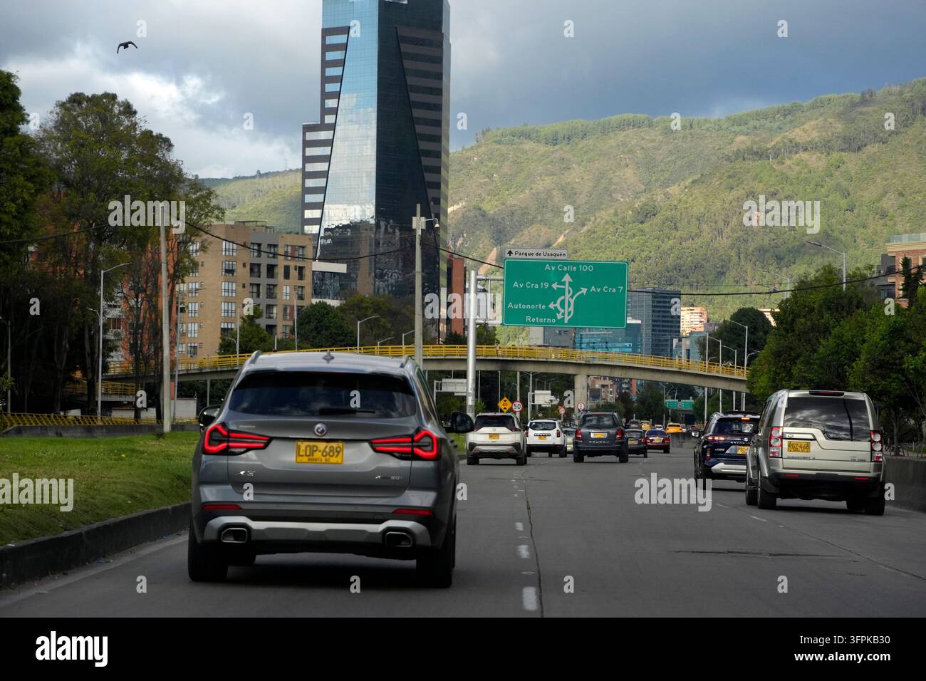 BOGOTA, KOLUMBIEN - 1. NOVEMBER 2025: Starker Verkehr fließt entlang der Autopista Norte in Bogota, Kolumbien, mit grünen Andenhügeln und modernen Wolkenkratzern sichtbar Stockfoto