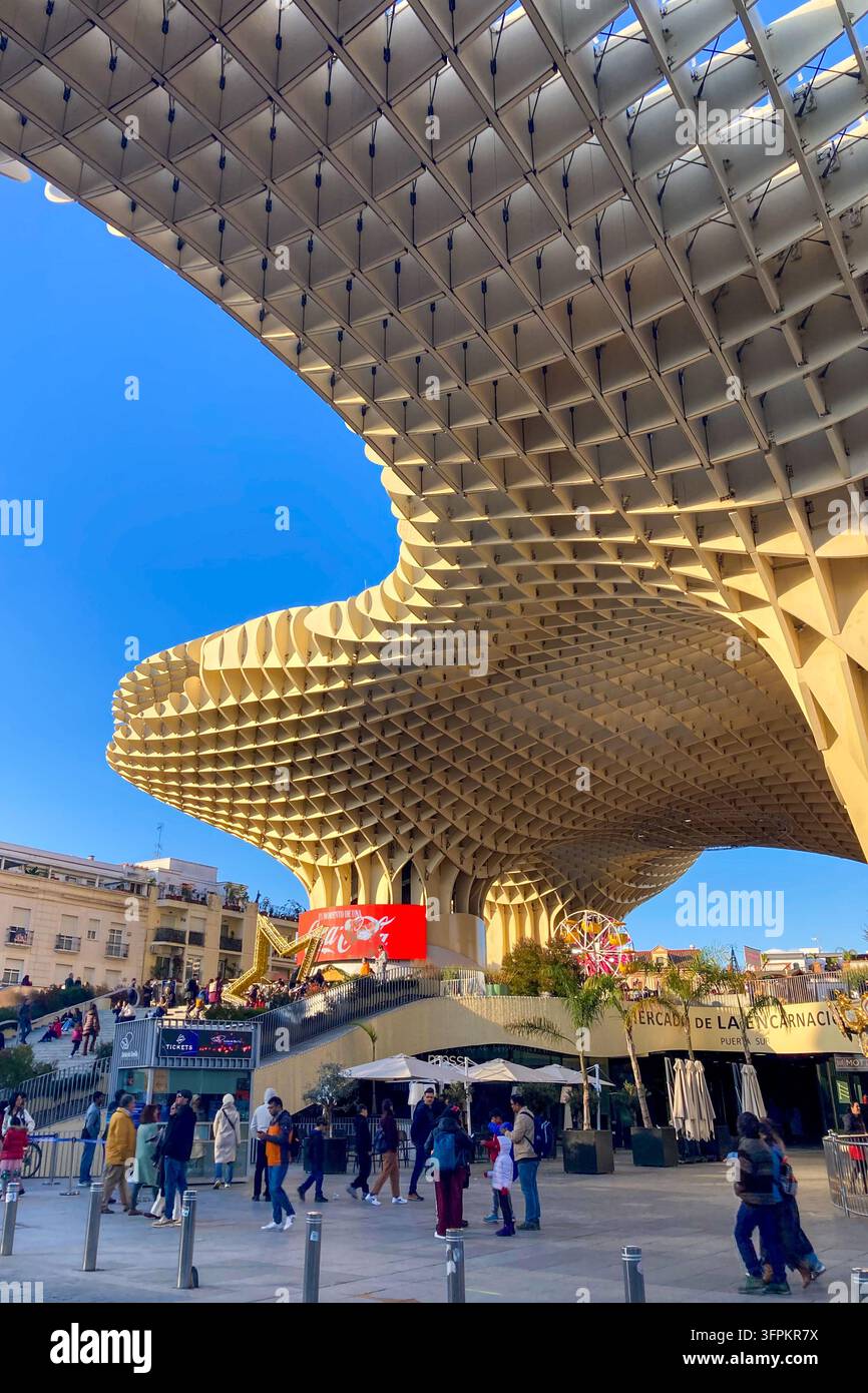 SEVILLA, SPANIEN - 25. DEZEMBER 2025: Ein festlicher Weihnachtsmarkt füllt den Platz unter den ikonischen Setas de Sevilla und schafft eine lebhafte Feierszenen - Smartphone-aufgenommenes Stockfoto