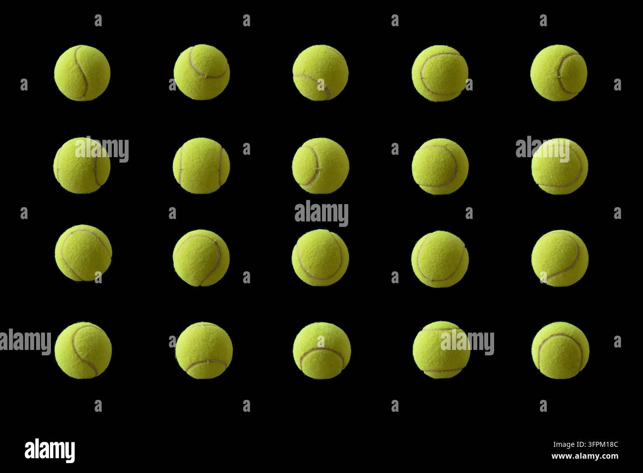 Zwanzig gelbe Tennisbälle, die in vier Reihen gegen einen schwarzen Hintergrund angeordnet sind, zeigen verschiedene Nahtausrichtungen, Textur, Symmetrie und Studiolicht. Stockfoto