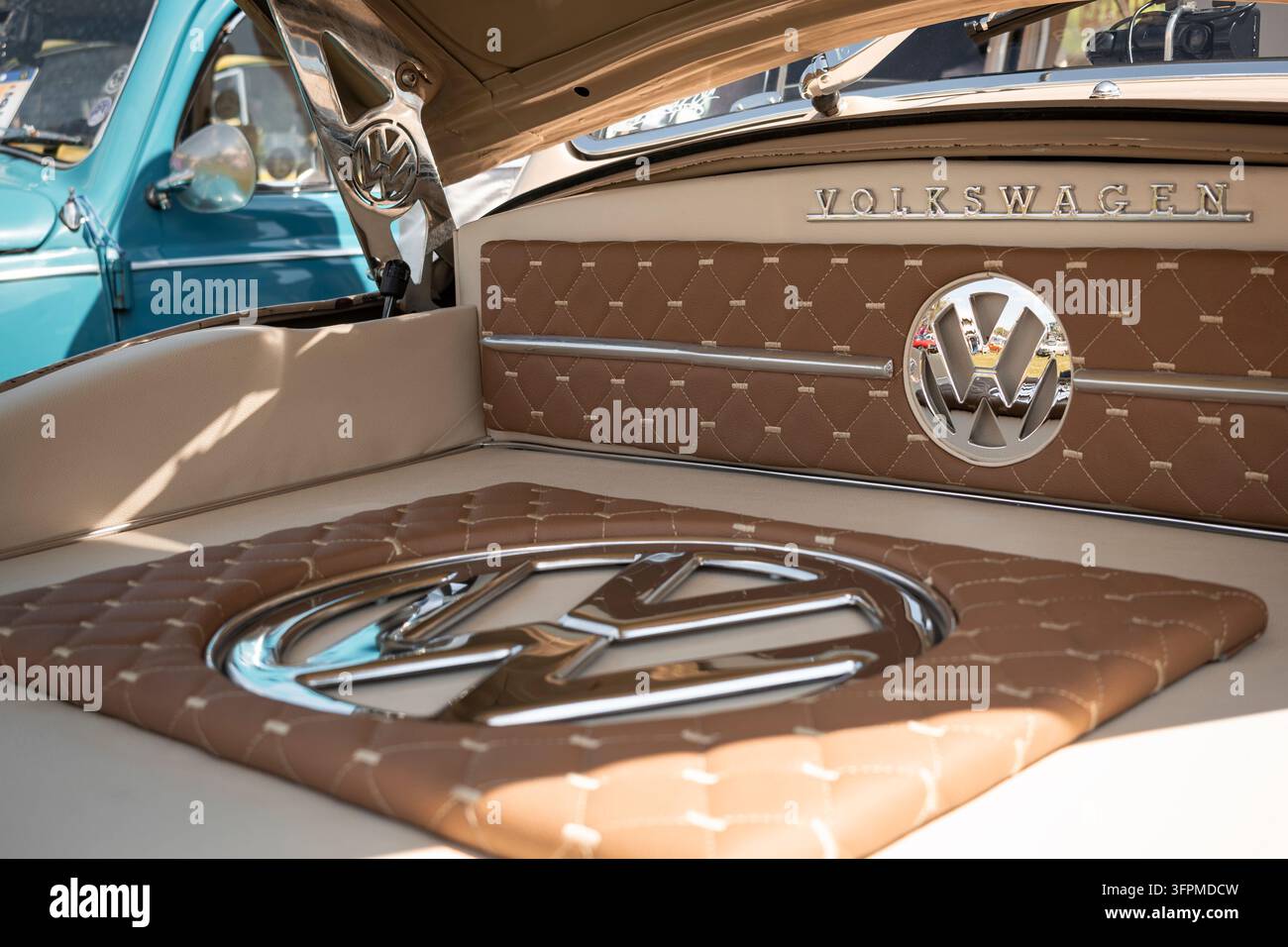 Vintage-Volkswagen-Beetle-Kofferrauminnenraum mit gesteppter Polsterung und Chrom-VW-Emblemen, der klassische Handwerkskunst zeigt. Stockfoto