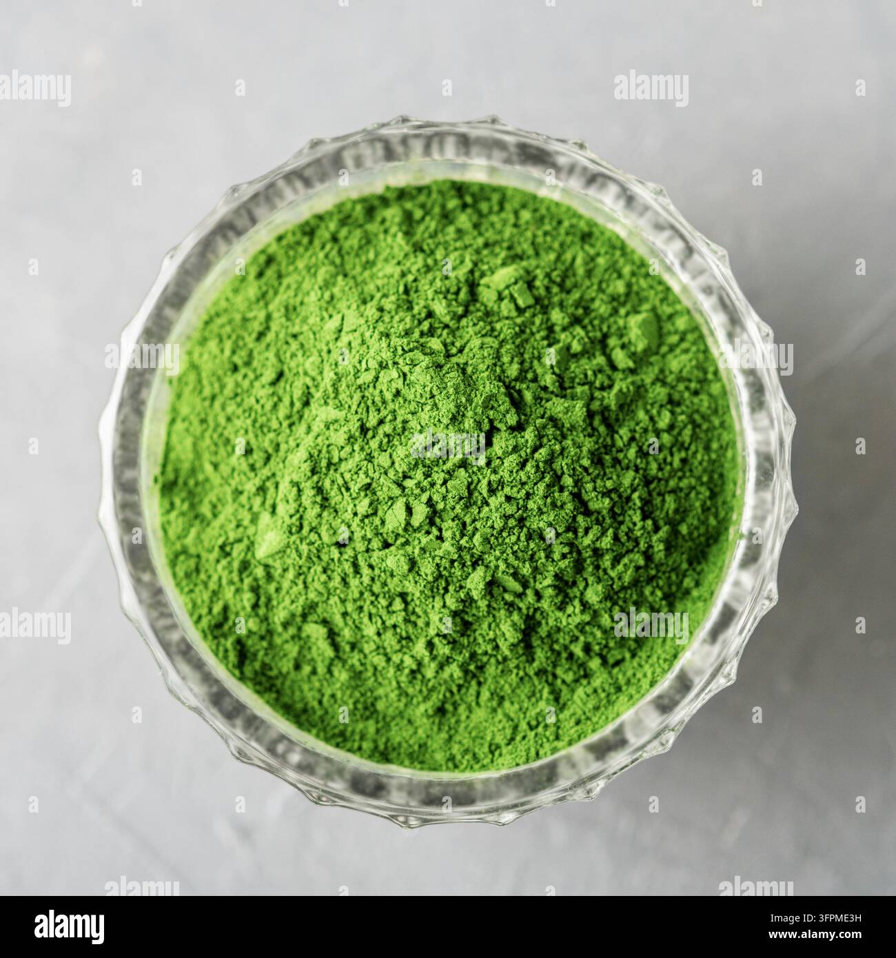 Zerteilte Chlorella oder Spirulina in einem Glasbecher auf grauem Beton. Oberblick. Stockfoto