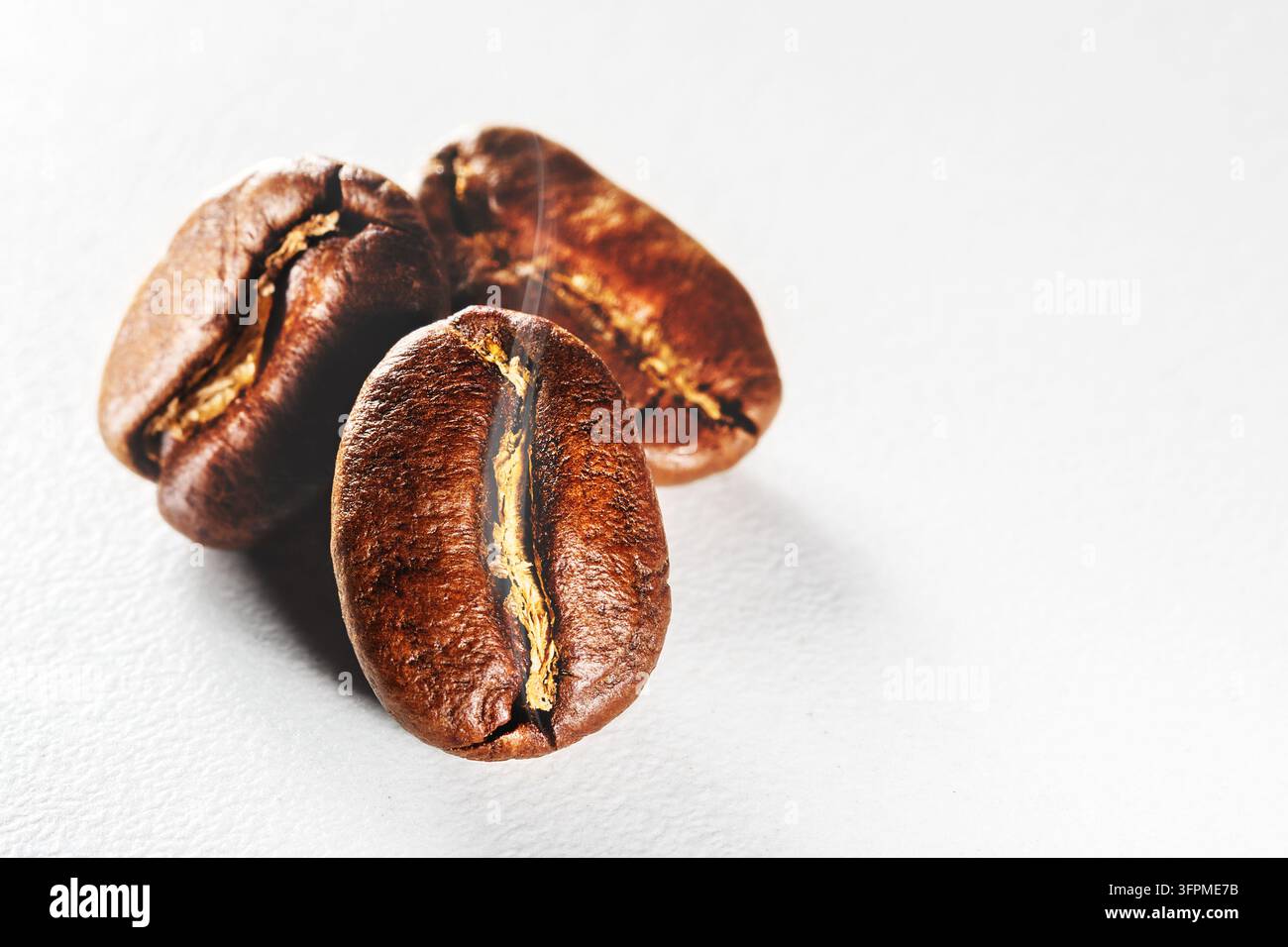 Geröstete Kaffeebohnen mit aromatischem Rauch auf weißem Hintergrund. Stockfoto