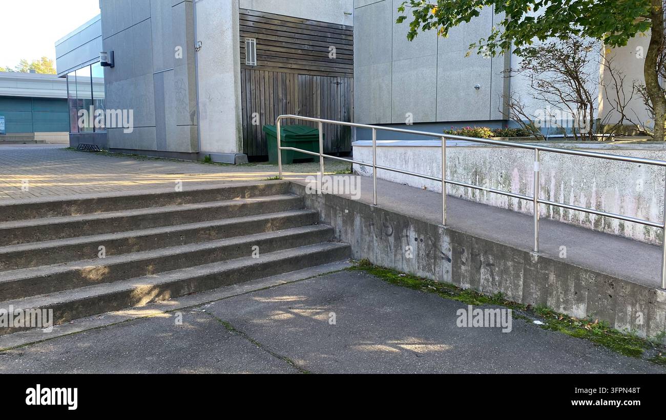 Betonstufen und zugänglicher Rampenabsatz mit Metallgeländer vor einem modernen öffentlichen Gebäude Stockfoto