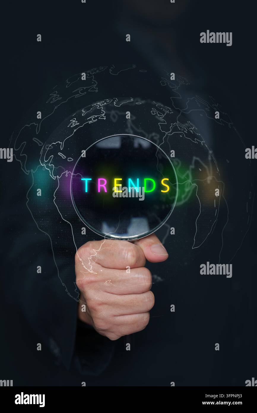 Globales Trendkonzept. Hand hält eine Lupe mit farbigem Text über einer digitalen Weltkartenglobus, Marktforschung, Geschäftsprognose, Industrie Stockfoto