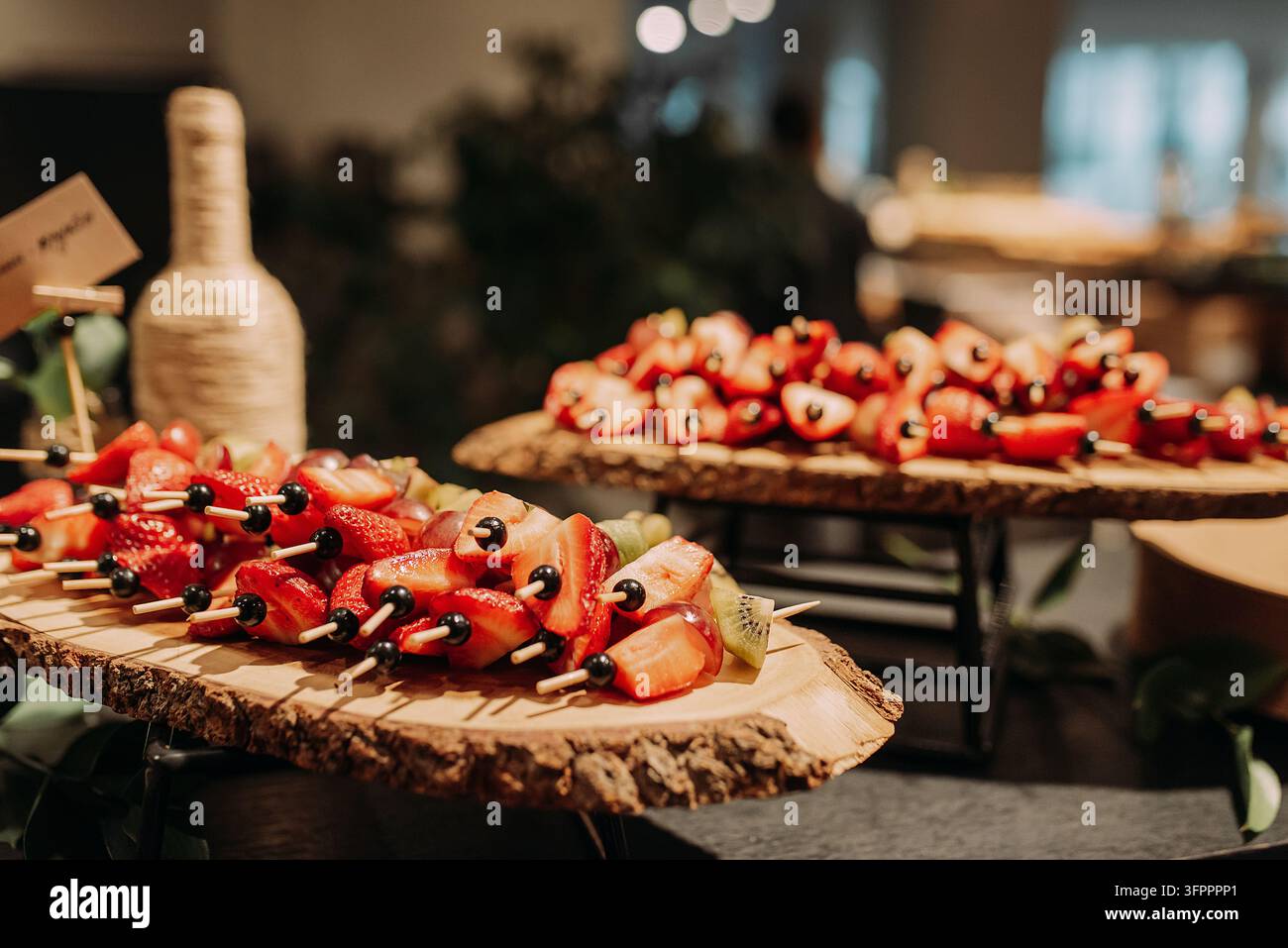 Frische Obstspieße, die auf rustikalen Holzbrettern an einem Buffet serviert werden Stockfoto