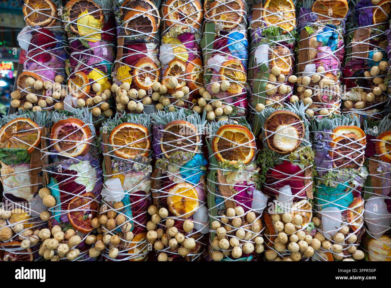 Eine Sammlung von handgefertigten Smudge-Stäbchen, die mit natürlichen Kräutern, getrockneten Zitrusfrüchten und aromatischen Pflanzenstoffen für Reinigungsrituale gefertigt wurden Stockfoto