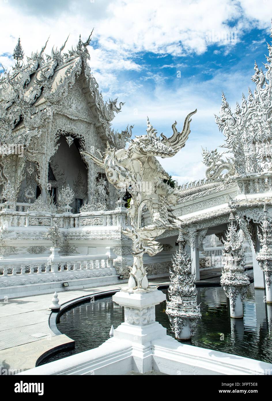 Komplexe weiße Tempelstruktur mit kunstvollen Designs und Wasserflächen während des Tages, Chiang Rai, Thailand Stockfoto