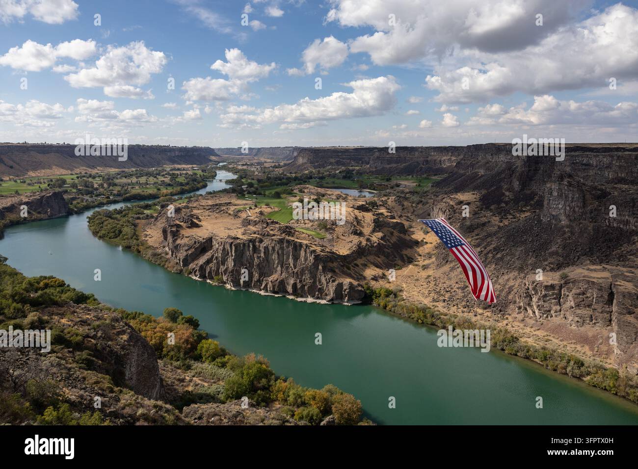 Eine amerikanische Flagge hängt über dem gewundenen Snake River in Twin Falls, Idaho, mit steilen Canyonwänden, grüner Vegetation und einem malerischen Flusstal darunter Stockfoto
