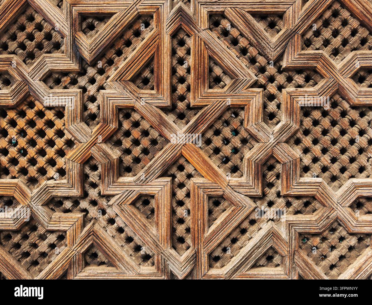 Gitterwerk aus Holz, geometrische Schnitzereien und Muster in einem Spindelgemälde im historischen Medresa El Bouanania. Stockfoto