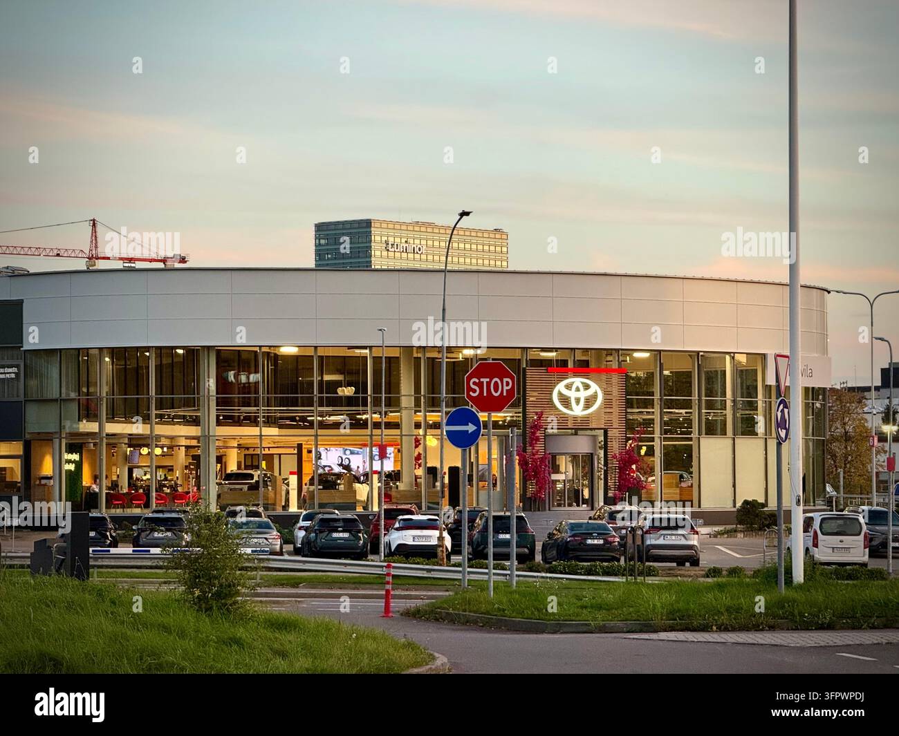 Ein weitwinkliges horizontales Foto des Tokvila Toyota-Händlergeschäfts und Servicegebäudes in Vilnius, Litauen, mit einer geschwungenen Glasfassade - Smartphone-aufgenommenes Stockfoto
