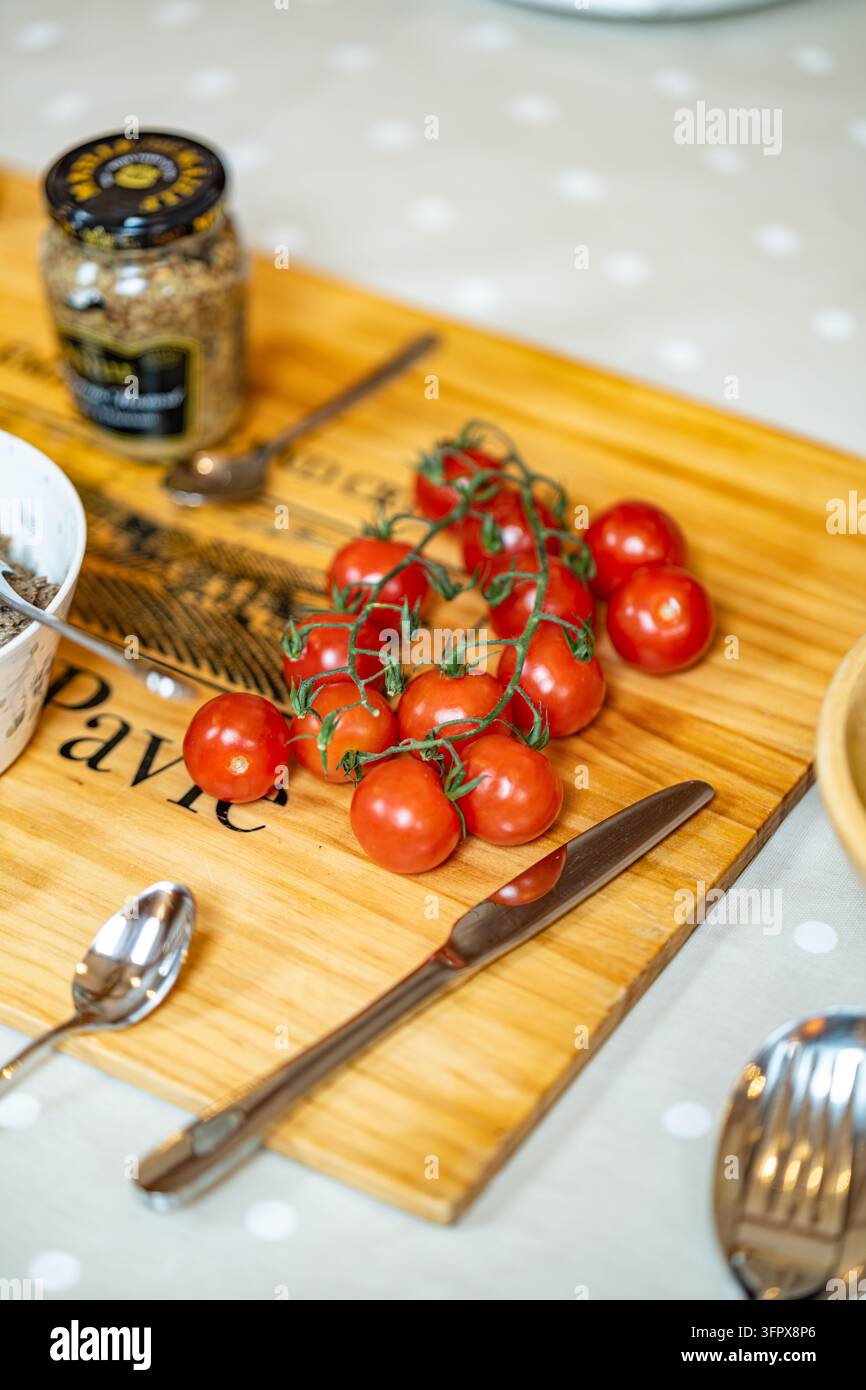 Kirschtomaten an der Ranke auf einem Holzbrett, das für ein Shoot-Lunch in einem Jagdhaus in Glen Clova, Angus, Schottland ausgelegt ist Stockfoto