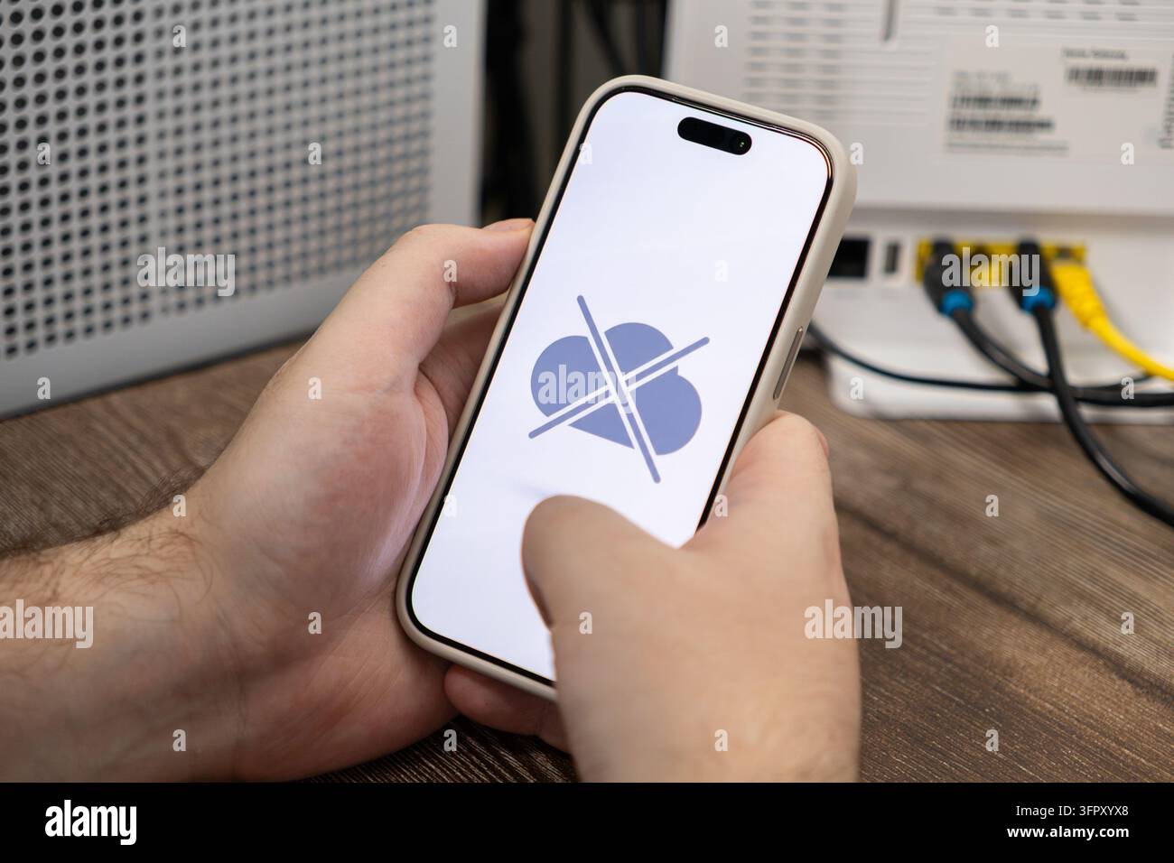Benutzer hält ein Telefon mit einem getrennten Cloud-Symbol auf dem Bildschirm, das technischen Ausfall oder Netzwerksignalverlust in der Nähe eines Breitbandgeräts für con darstellt Stockfoto