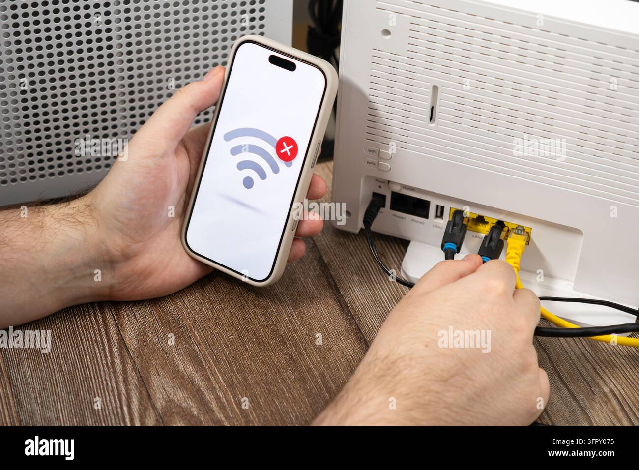 Techniker prüft die Internetverbindung, indem er Ethernet-Kabel an einem modernen Router anpasst, während ein Smartphone ein Symbol für eine unterbrochene Verbindung anzeigt, um zu illustrieren Stockfoto