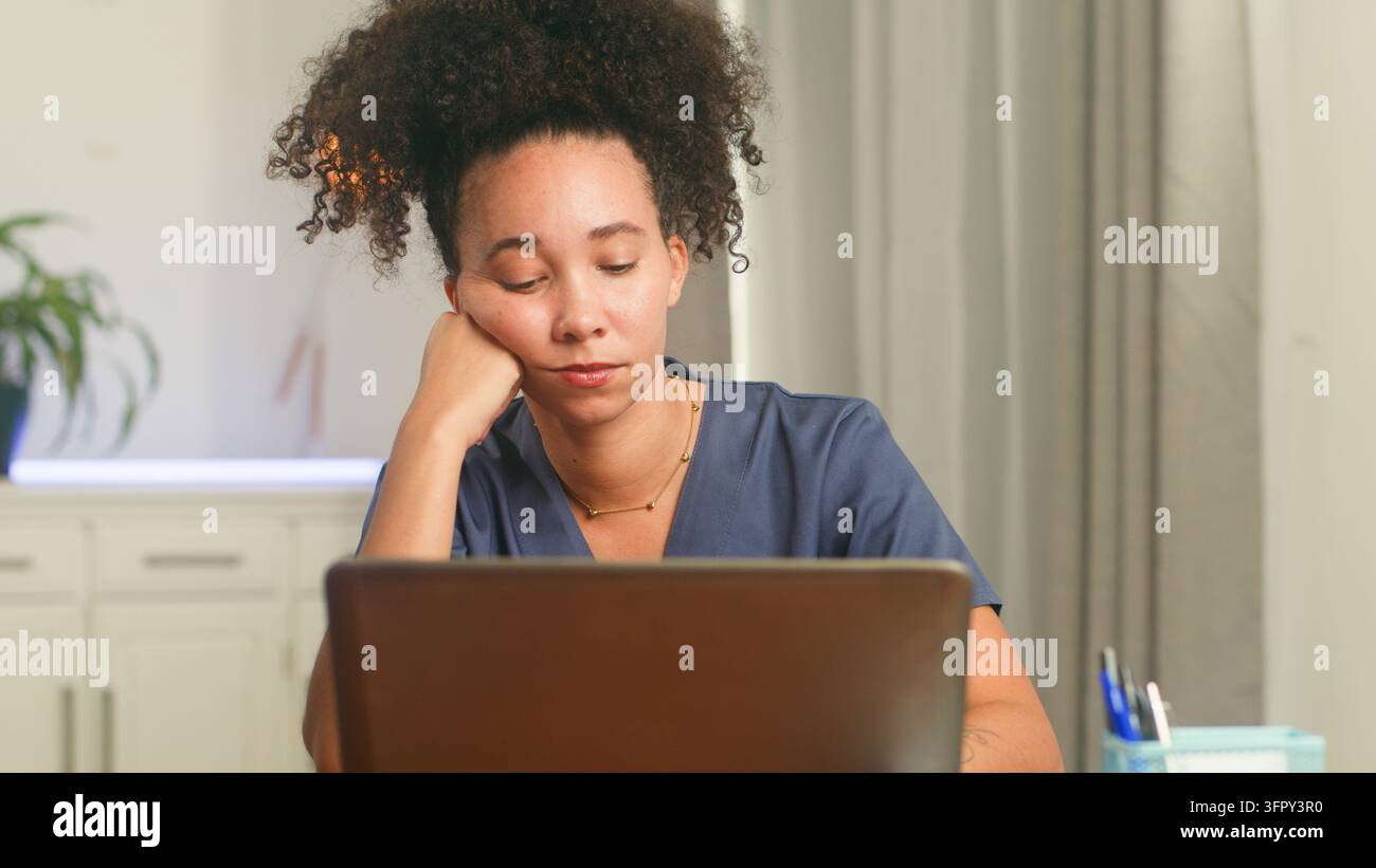 Frau arbeitet an einem Laptop mit Stress und Burnout an ihrem Schreibtisch Stockfoto