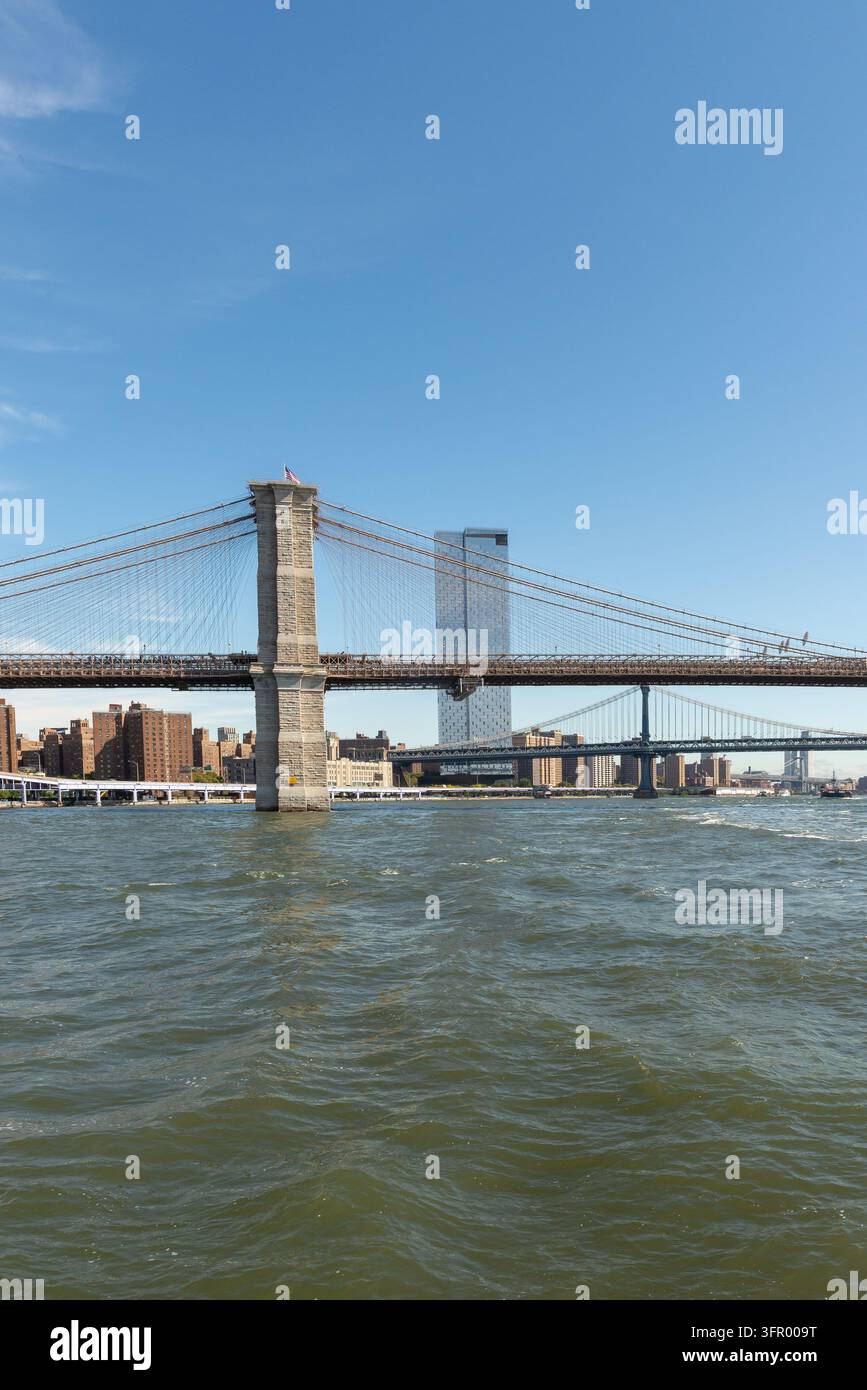 Die Brooklyn Bridge und die Manhattan Bridge überspannen den East River in New York City, gesehen vom Pier 15 am Wasserrand in Lower Manhattan. Die ikonische Suspe Stockfoto
