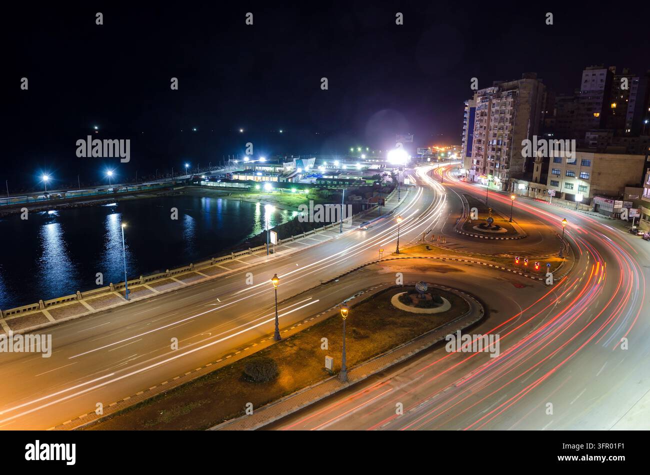 Der Verkehr fließt entlang der Küstenstraße bei Nacht. Stockfoto