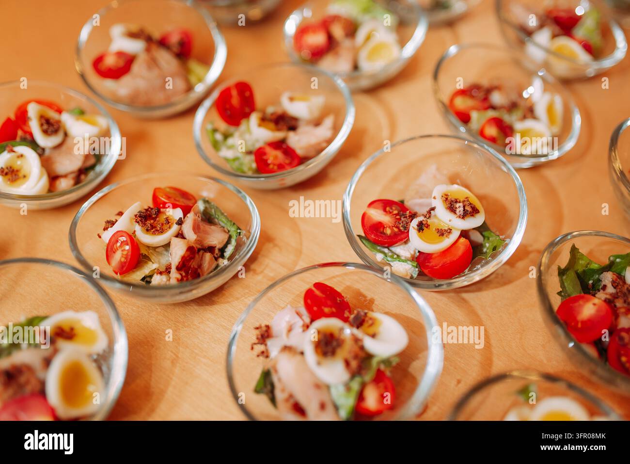 Individuelle Hühnersalat-Schüsseln mit gekochten Eiern und Kirschtomaten an einem Buffet Stockfoto