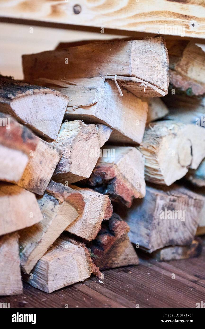 Gestapeltes Feuerholz, das unter einer Holzbank im Saunaraum gelagert ist. Nahaufnahme von gehackten Holzscheiten, die zum Heizen vorbereitet sind, rustikale Spa-Atmosphäre und natürliches Wellness-Konzept Stockfoto