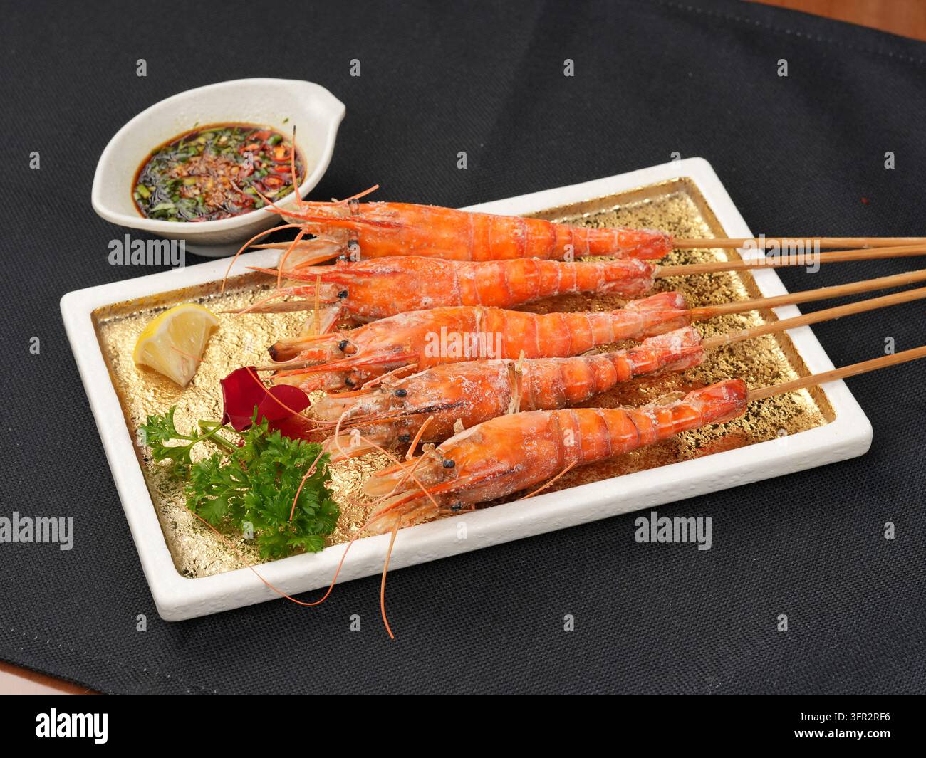 Salzgegrillte Garnelen auf rechteckigem weißem Teller mit Spießen und Salz-Pfeffer-Dip Stockfoto